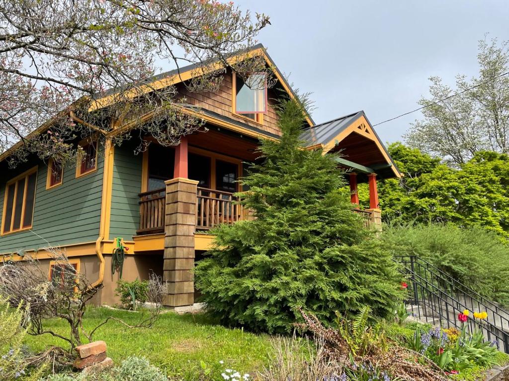een groen huis met een balkon en een boom bij Alberta Arts Craftsman ADU in Portland