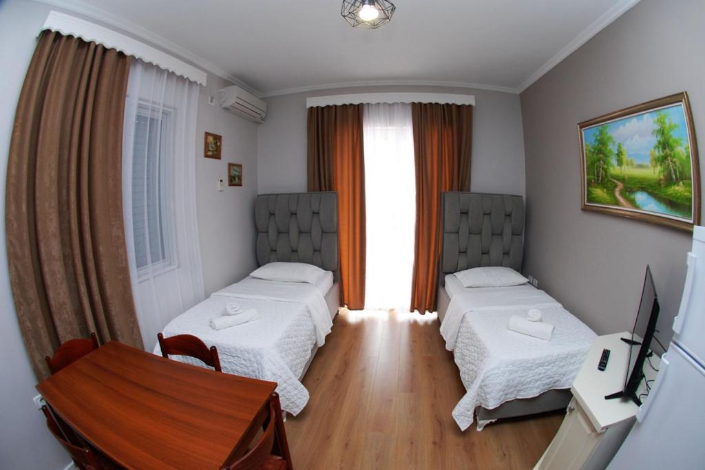 a room with two beds and a table and a television at Hotel Vila Alvin & Apartments in Sarandë