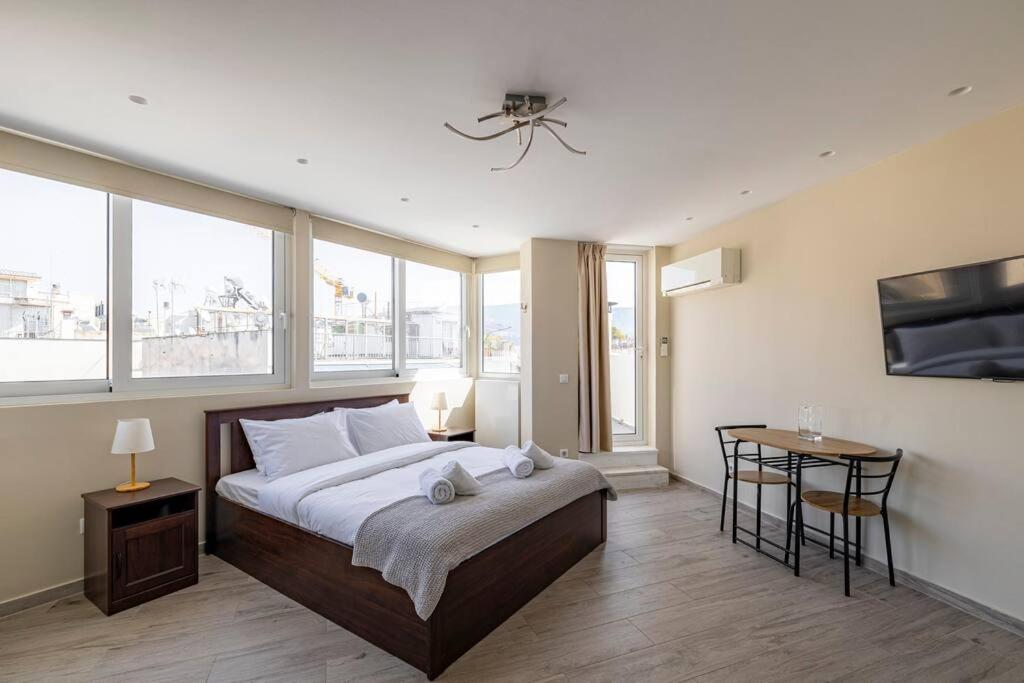 a bedroom with a large bed and a table and windows at Penthouse in the heart of Athens in Athens