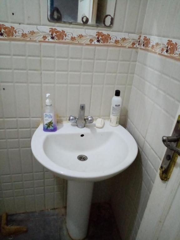 a white sink in a bathroom with white tiles at Beda in Madīnat as Sādāt