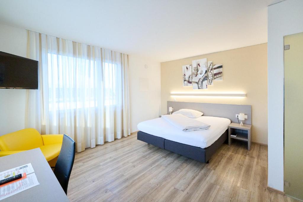 a hotel room with a bed and a chair and a television at Hotel am Kreisel Self-Check-In by Smart Hotels in Lachen