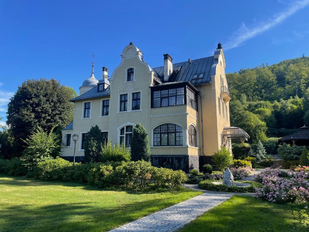 a large white house with a garden in front of it at Villa Elise Park Pension in Stronie Śląskie