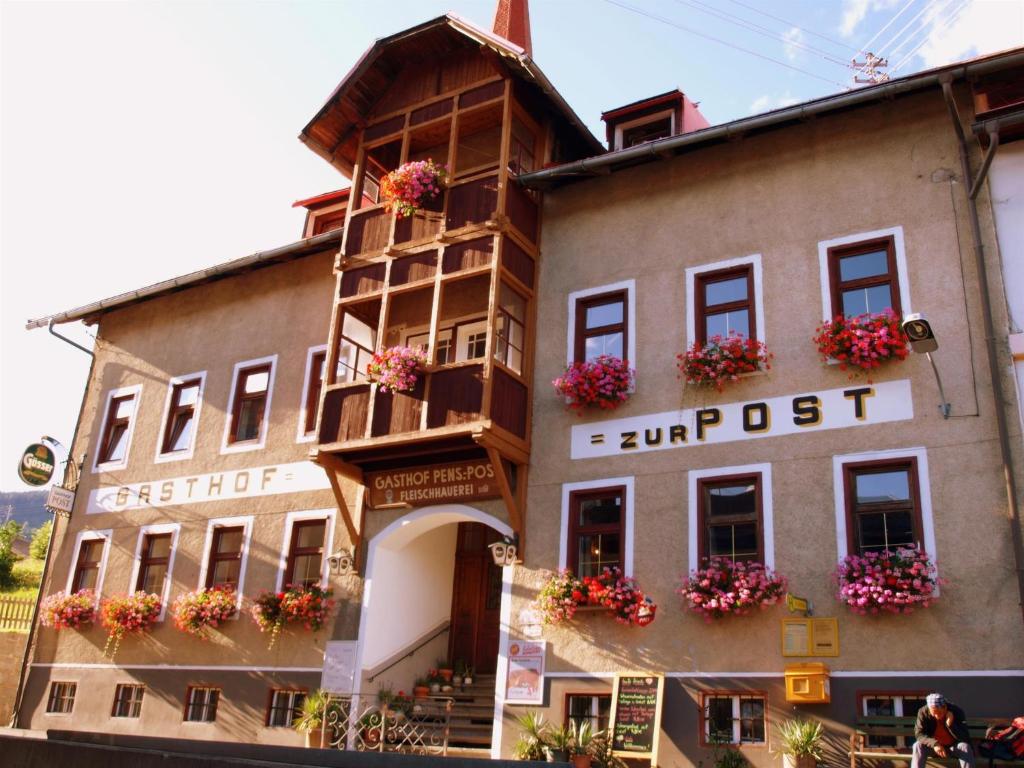 un edificio con cajas de flores en la parte delantera en Gasthof zur Post, en Sankt Lorenzen im Lesachtal