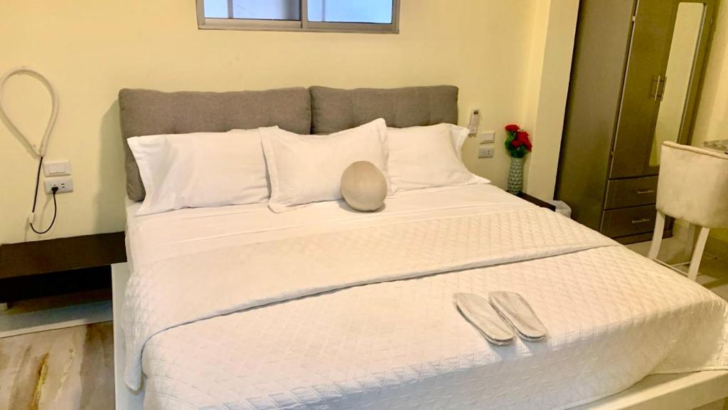Una gran cama blanca con dos zapatillas de plata. en Microsuite 1 hermosa y privada, en Guayaquil