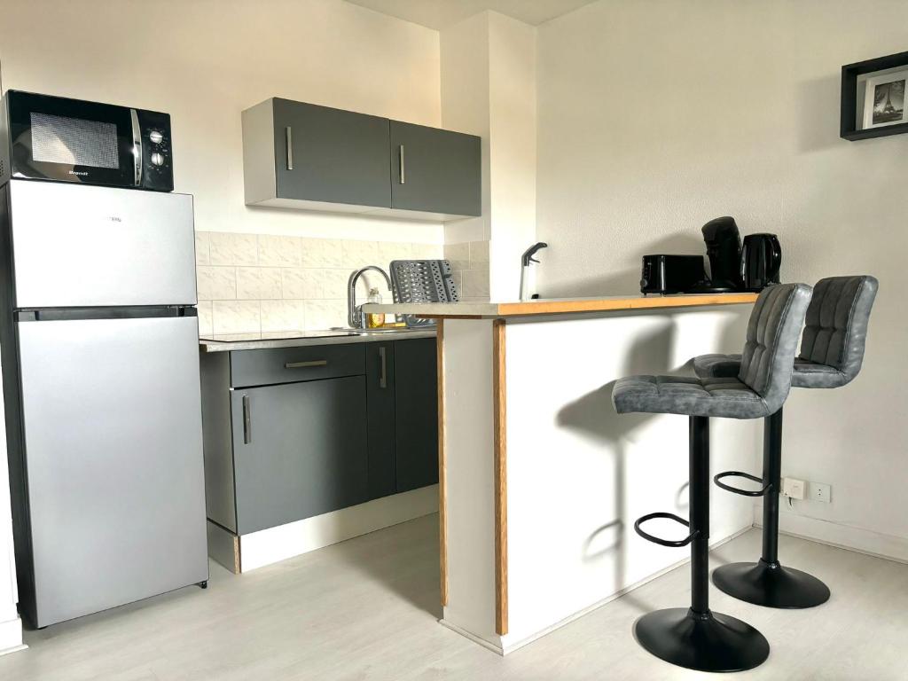 eine Küche mit einem weißen Kühlschrank und 2 Barhockern in der Unterkunft New Studio Cosy - Proche RER et centre ville in Brétigny-sur-Orge