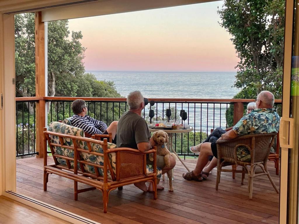 a group of people sitting on a porch with a dog at The Dunes *Beachfront* Lake Tyers Beach in Lake Tyers