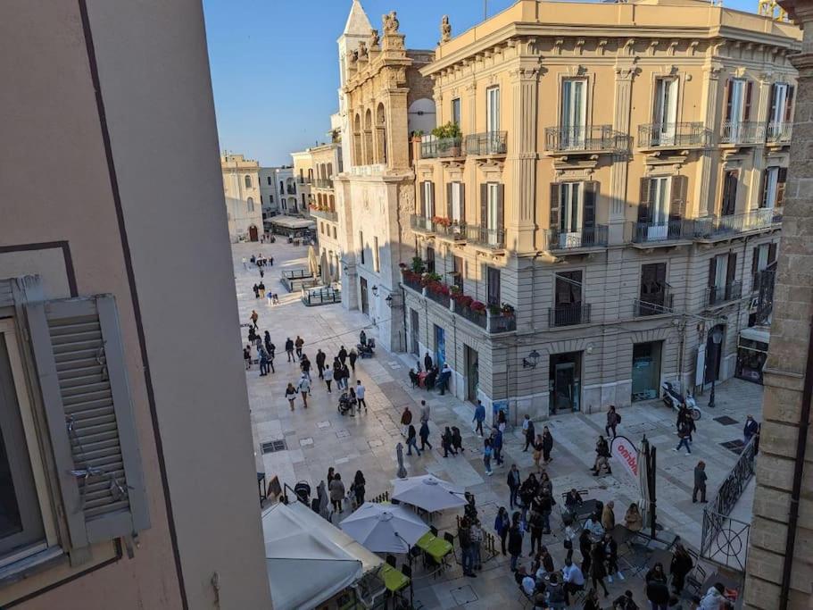 un grupo de personas caminando por una calle de la ciudad en A balcon on the plaza, en Bari