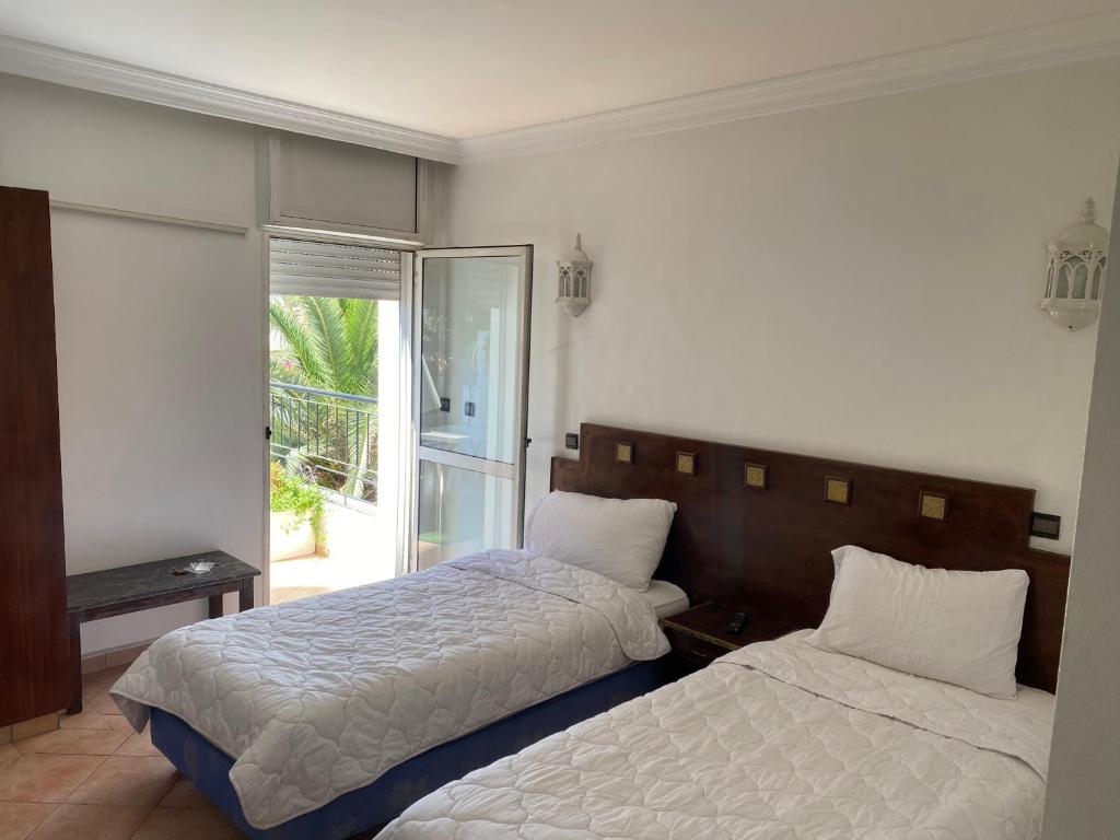 1 dormitorio con 2 camas y ventana en Hotel Merry en Agadir