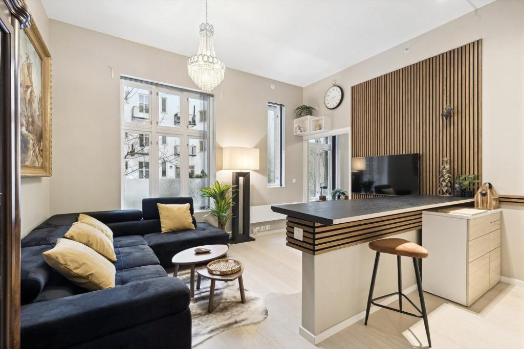 a living room with a blue couch and a kitchen at Nordic Fjordside Residence in Oslo