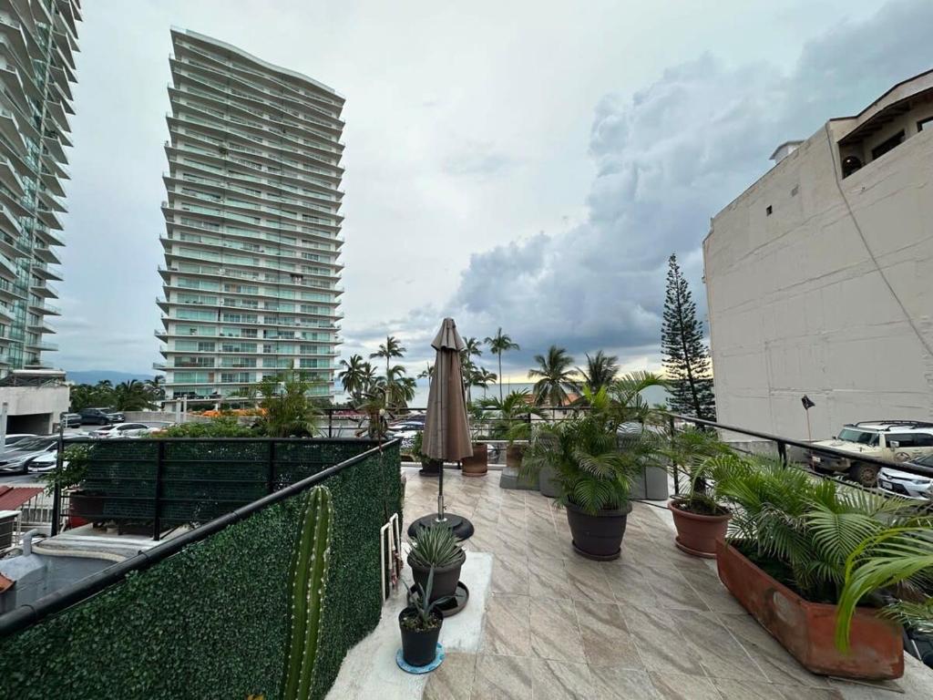 un balcón con plantas, sombrilla y edificios en 2 BR Penthouse Condo Puerto Vallarta, en Puerto Vallarta