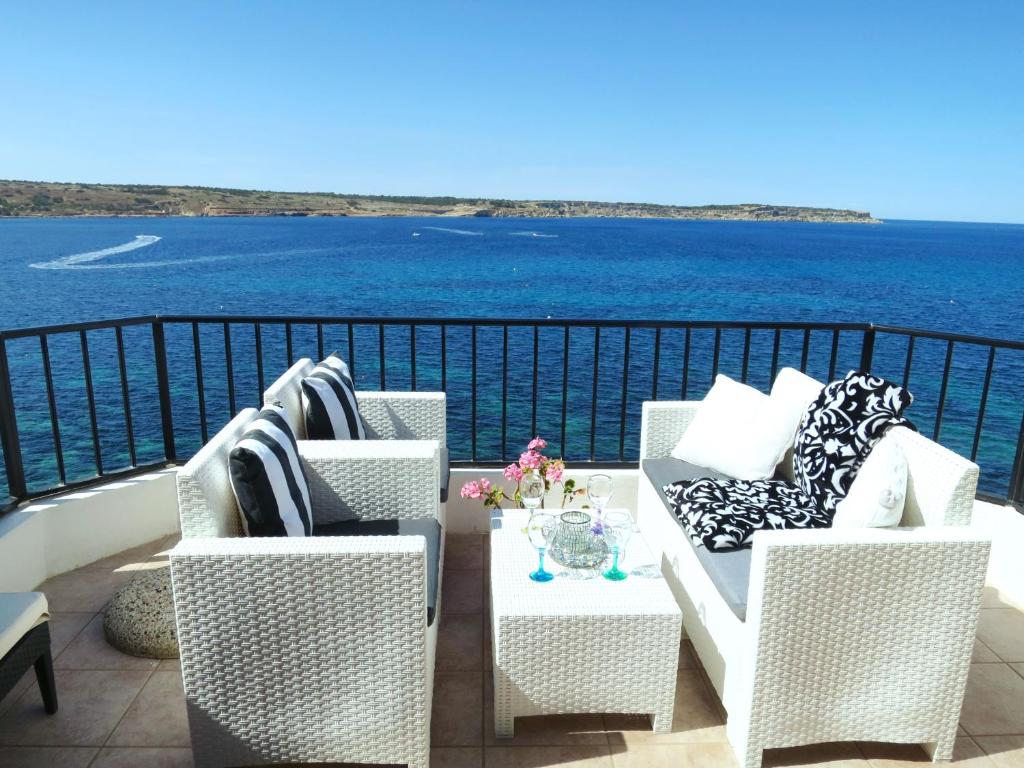 einen Balkon mit Stühlen und einem Tisch mit Blick auf das Wasser in der Unterkunft Seafront apartment Terrace, lounger & Panoramic ocean views in Mellieħa