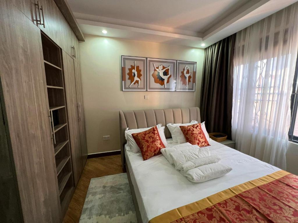 sypialnia z dużym łóżkiem z poduszkami w obiekcie KAVOD FURNISHED APARTHOTELS w mieście Kampala