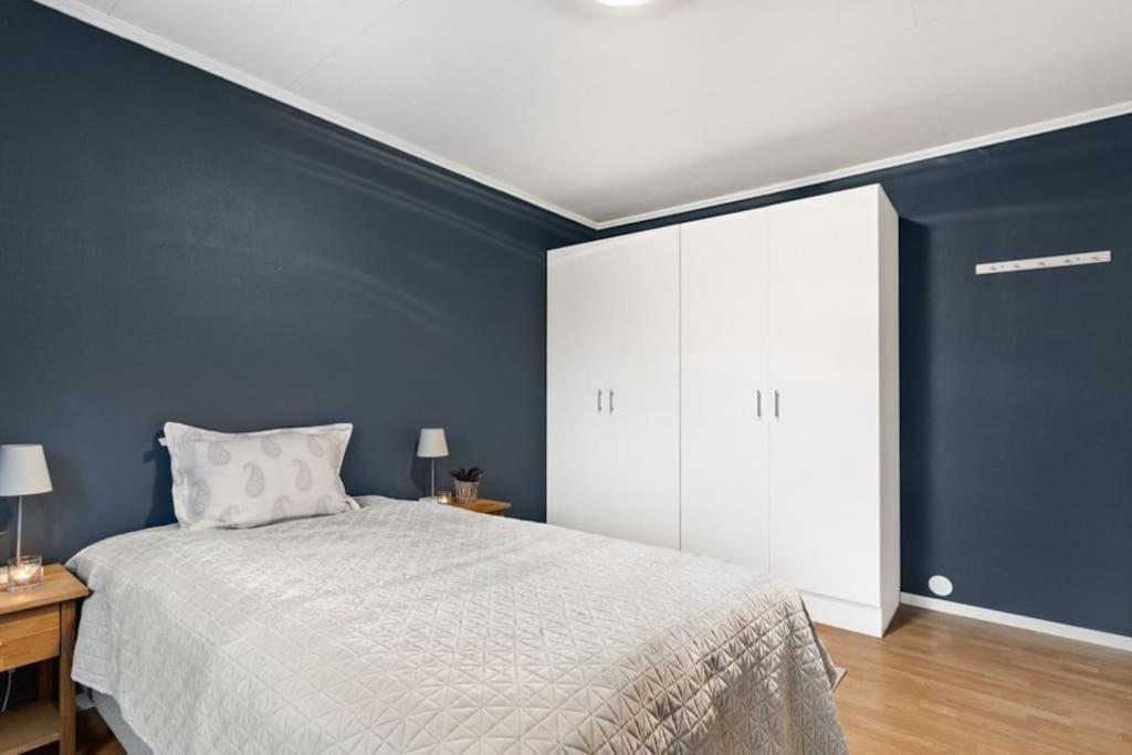 1 dormitorio con cama blanca y pared azul en Cozy and central home near Oslo Gardermoen Airport en Eidsvoll