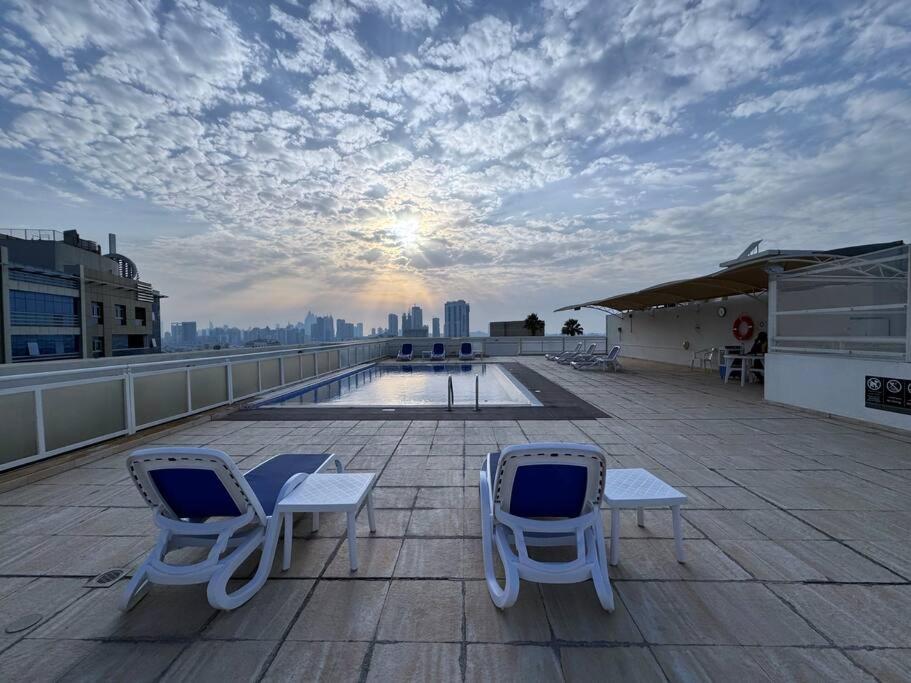 two chairs and a pool on the roof of a building at Get Rooftop Pool at 2BR APT Near Mall Of Emirates 411 in Dubai