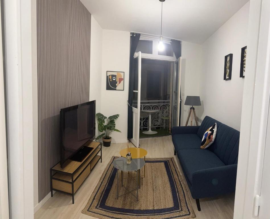 uma sala de estar com um sofá azul e uma televisão em Apparemment cosy et chaleureux em Montauban