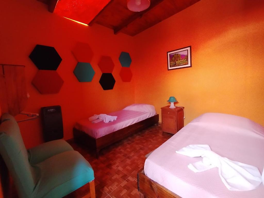 a red room with two beds and a chair at Hospedaje Miguel in Maimará