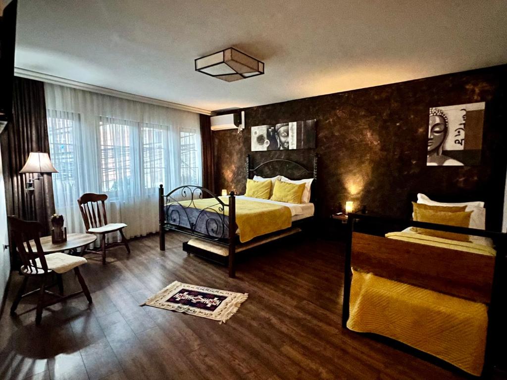 a bedroom with two beds and a table and a chair at Hotel Fjorr in Prizren