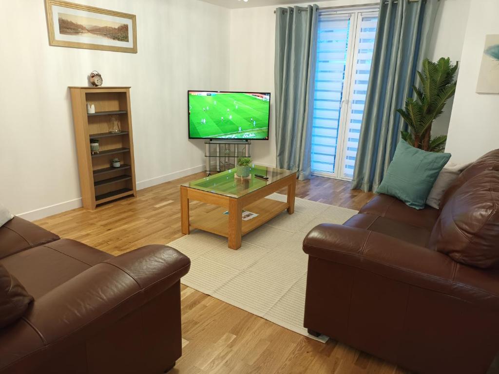 a living room with a couch and a tv at Spacious Elegant 2-BR Apartment in Aberdeen City Centre in Aberdeen