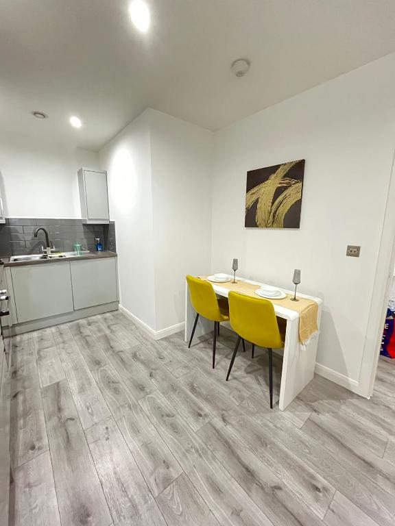 a kitchen with a table and yellow chairs in a room at Leicester City Centre Flat in Leicester