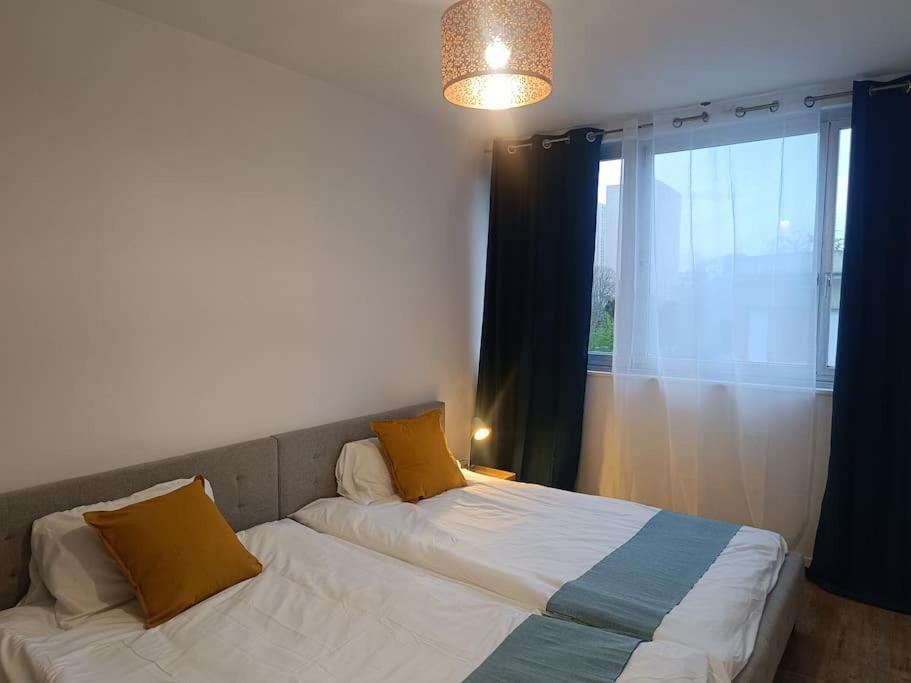 1 dormitorio con 2 camas y ventana en Appartement aux Portes de Paris, métro 12, en Aubervilliers