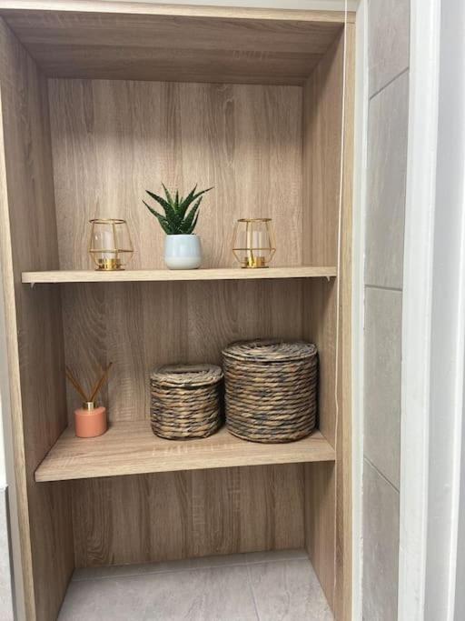 a wooden shelf with two baskets and two candles at Cute 2 bedroom house Littleover close to amenities hospital in Derby