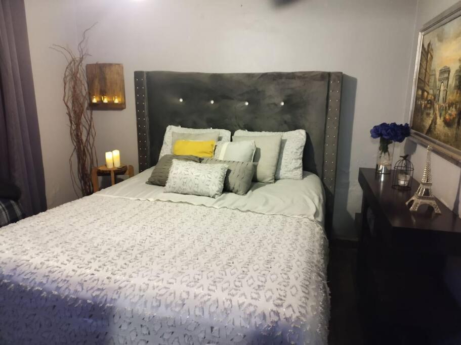 een slaapkamer met een groot bed met witte lakens en kussens bij Jardin Imperial in Mexicali