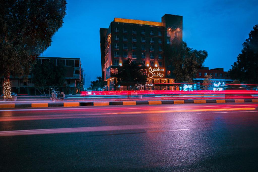 a city street at night with a building with red lights at Granada Hotel in An Najaf