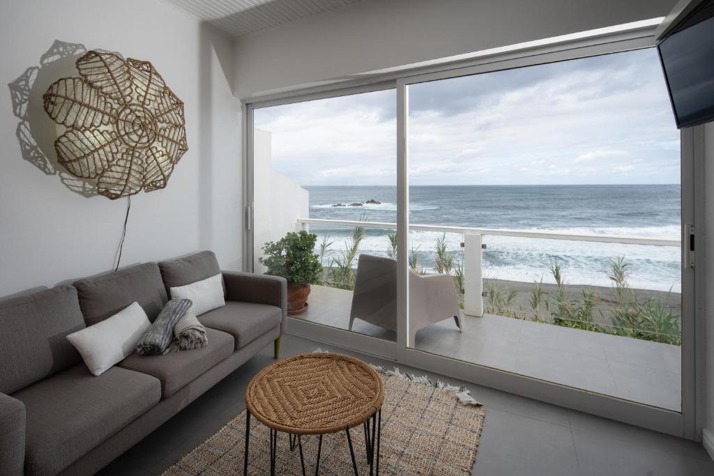 Una sala de estar con un sofá y vista al mar. en Casa Da Praia, en Porto Formoso
