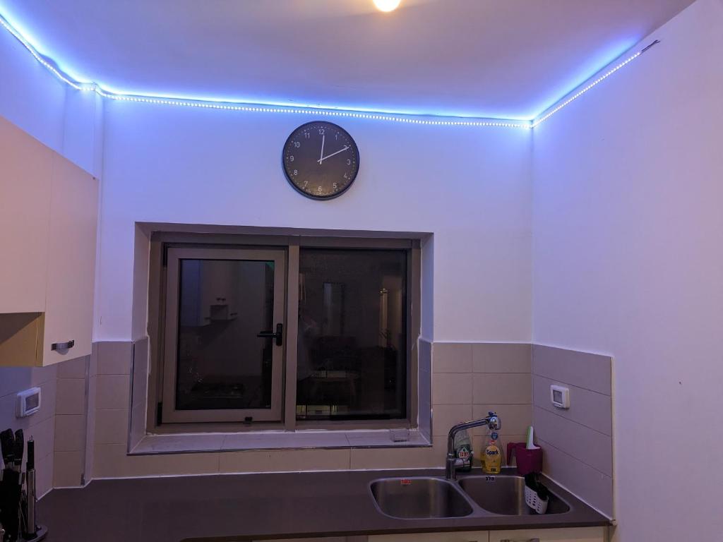 a clock on a wall above a kitchen sink at Private room in shared Apartment in Jerusalem