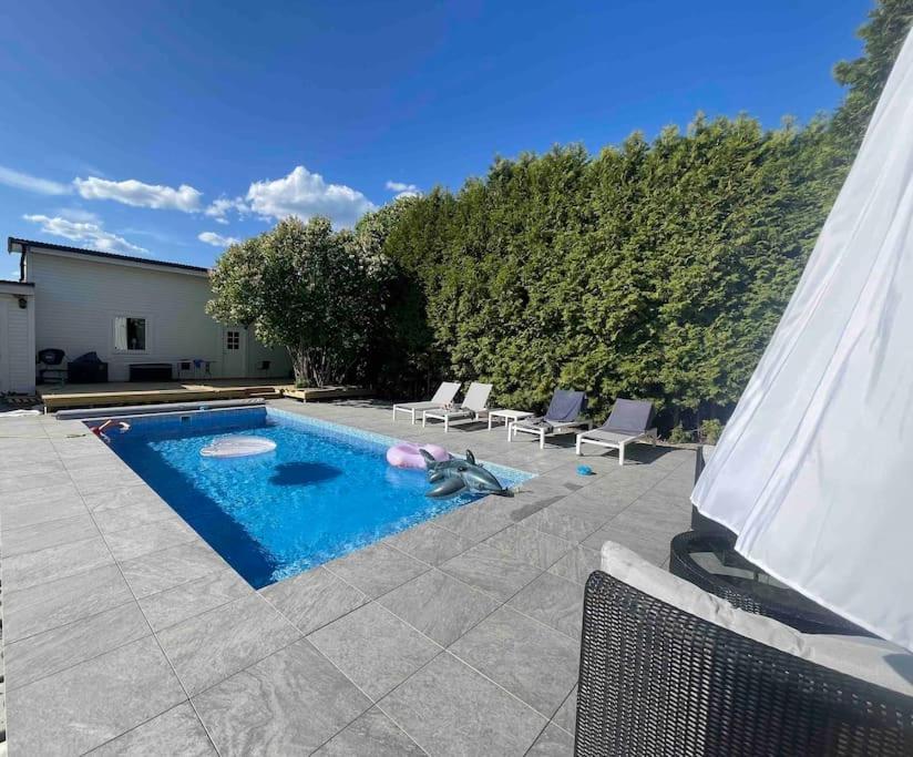 a swimming pool with two chairs next to a house at Centralt boende, pool, nära till natur & våtmark in Eskilstuna