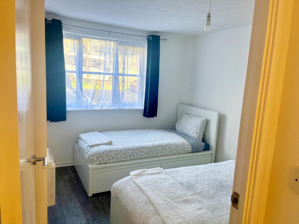 a bedroom with two beds and a window at Comfortable and Cosy London Stay in London