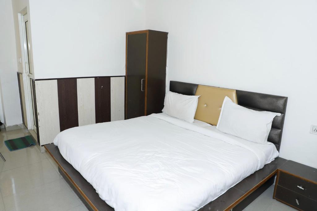 a large white bed with a wooden headboard in a room at Hotel elibrista in Meerut