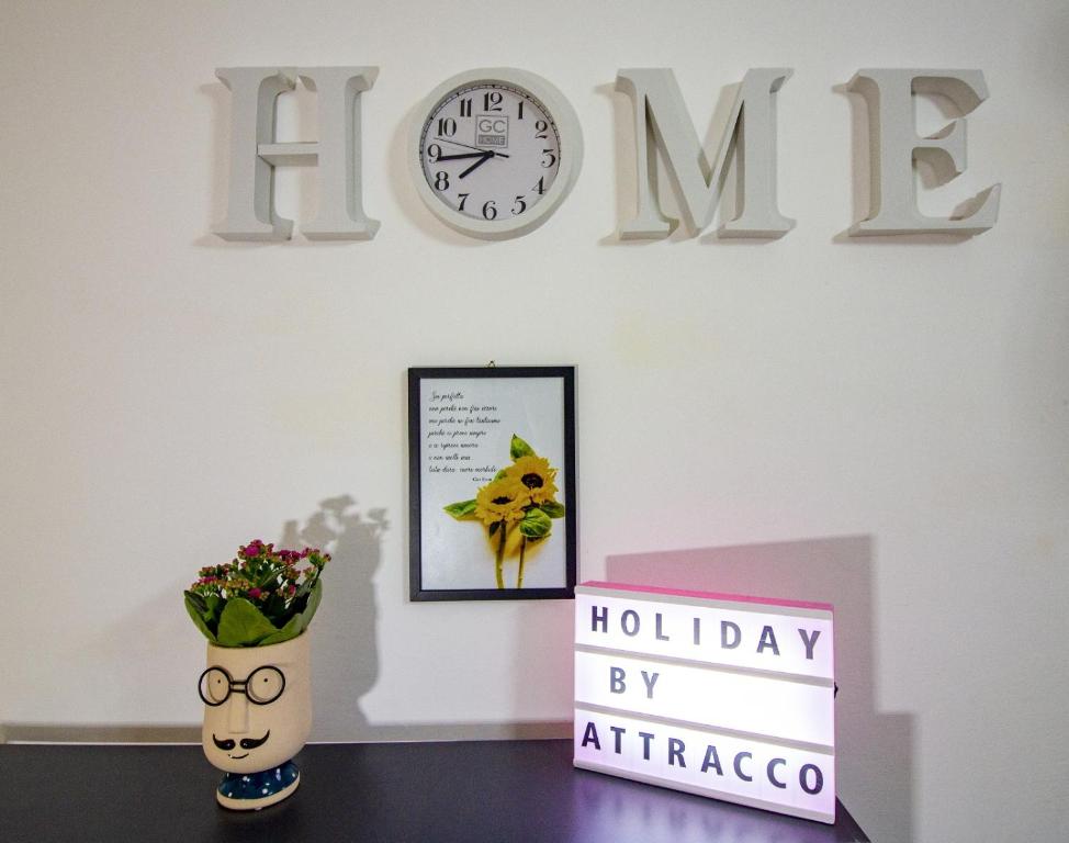 uma prateleira com um relógio e um vaso com flores em Attracco Apartment em Trapani