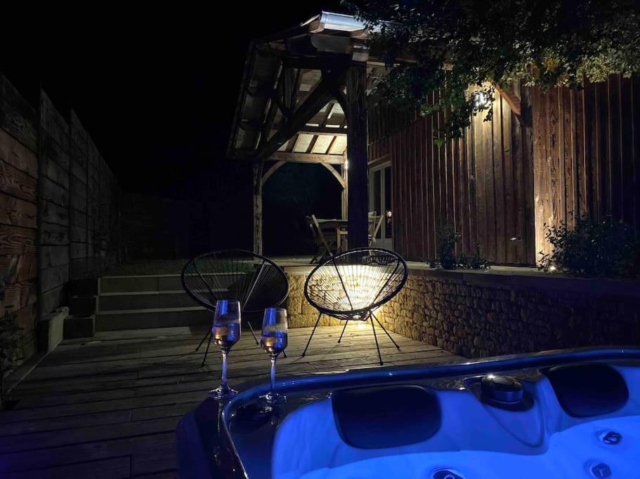 bañera de hidromasaje con 2 copas de vino y silla en Gîte avec spa, en Saint-Avit-Sénieur