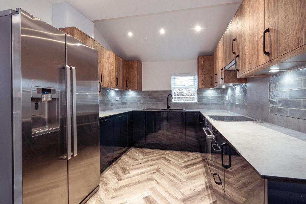 a kitchen with wooden cabinets and a stainless steel refrigerator at Ashley’s Place in Manchester