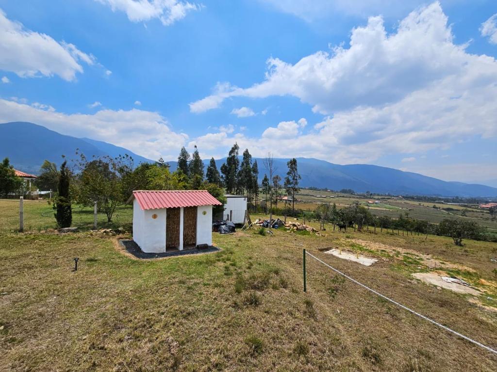 een klein huis in een veld met bergen op de achtergrond bij Zona de Camping El mirador in Villa de Leyva