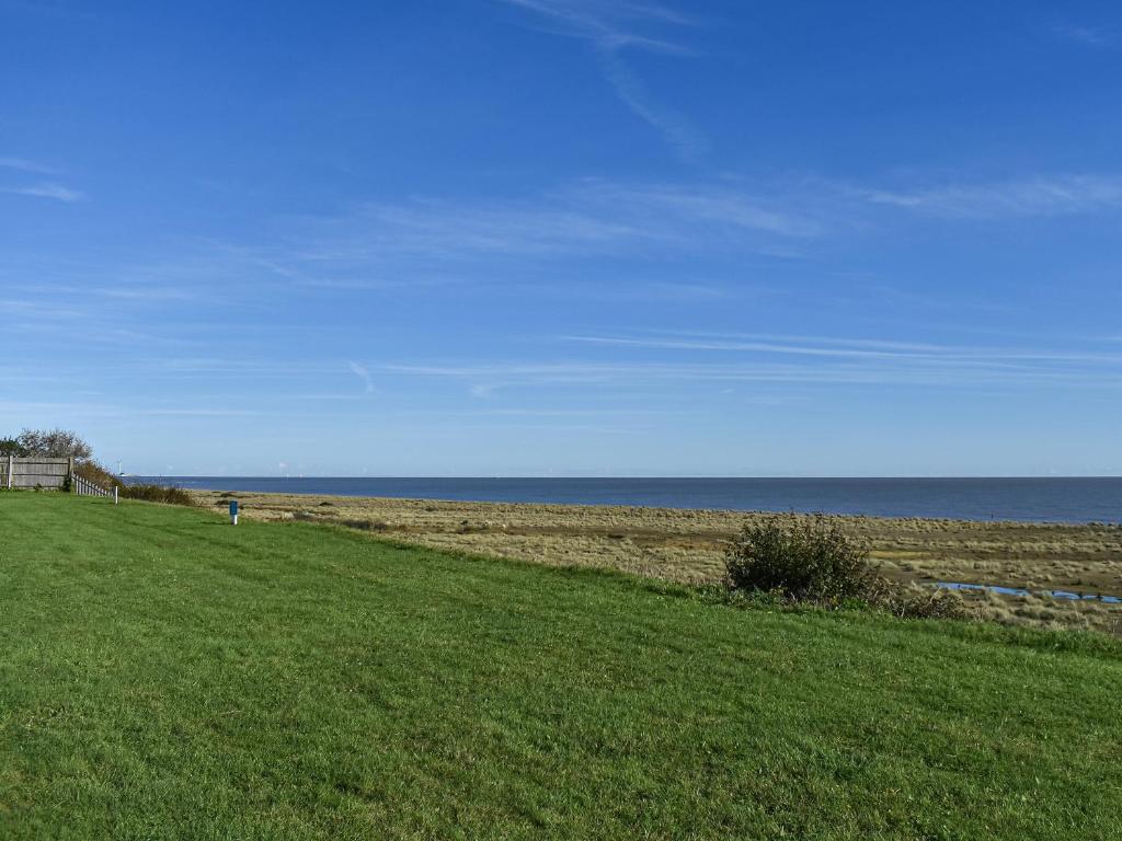 un campo verde con el océano en el fondo en Seascape, en Kessingland