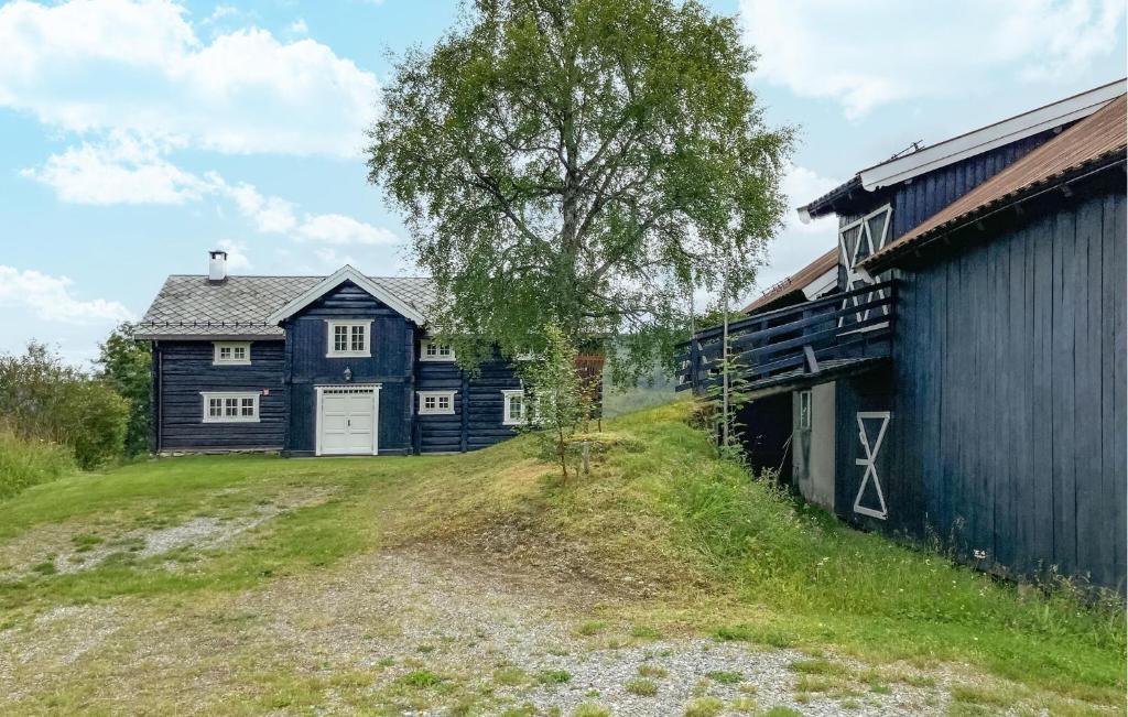 a blue house on a hill next to a barn at Stunning Home In Svatsum With House A Panoramic View in Svingvoll