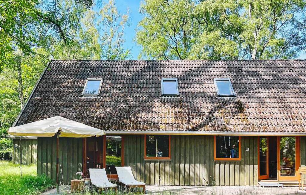 una casa verde con sillas y sombrilla en Stunning Home In Frederiksvrk With Wifi, en Frederiksværk
