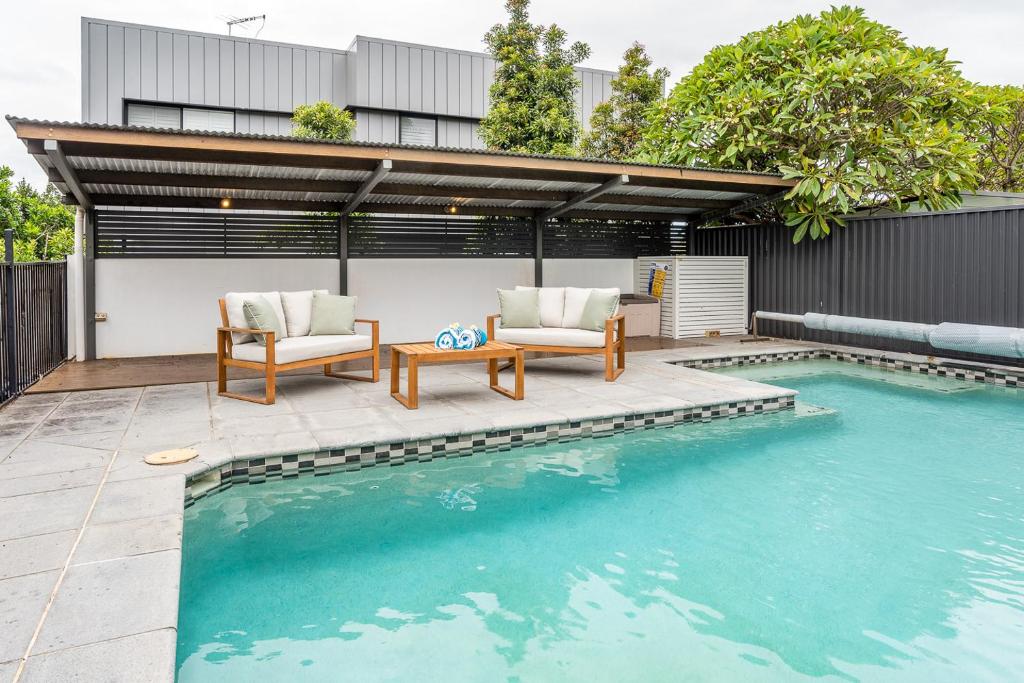 a swimming pool with two chairs and a table next to a house at Beautiful Modern Home in Heart of New Farm in Brisbane