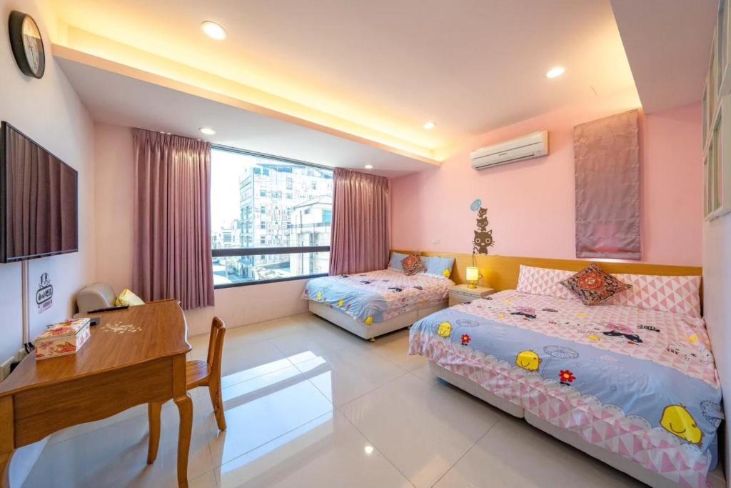 una camera da letto con due letti, un tavolo e una scrivania di 享樂民宿 可包棟 a Ji'an