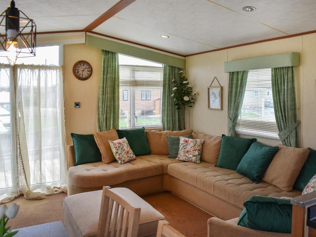 a living room with a large brown couch and windows at Skiddaw View Lodge in Plumbland
