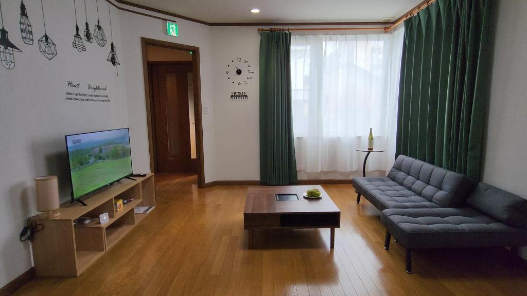 a living room with a couch and a television at SecondHouse Otaru Garden in Otaru