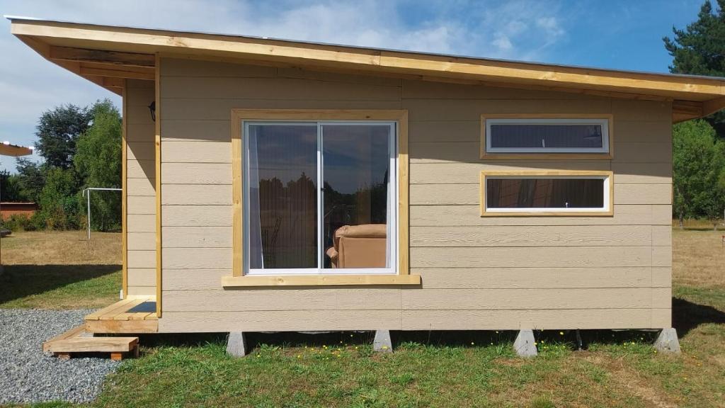 ein kleines Haus mit einem Fenster im Gras in der Unterkunft Cabañas Los Maitenes in Freire