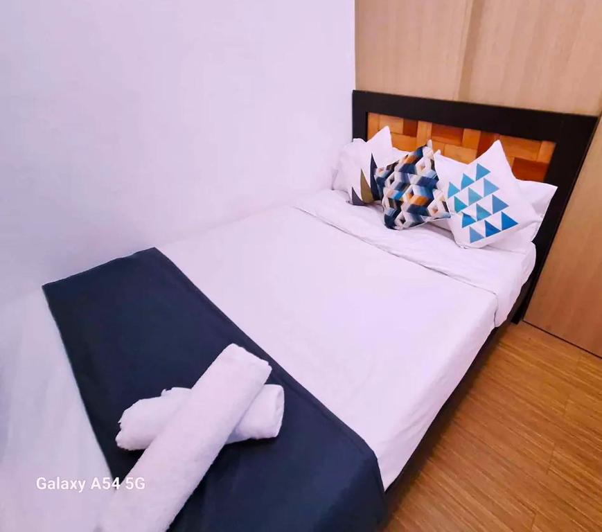 um quarto com uma cama com lençóis brancos e almofadas em Snuggle and Comfy 1BR with WiFi in Grace Residences Taguig City em Manila