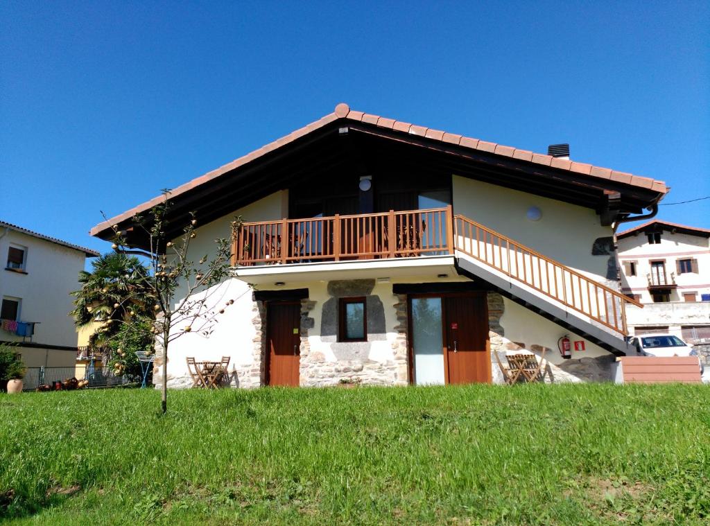 dom z balkonem na szczycie zielonego pola w obiekcie Apartamentos Aldagaia w mieście Hernani