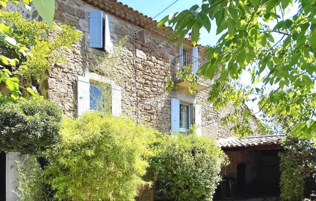 una vieja casa de piedra con árboles delante de ella en Arpege, en Vinezac