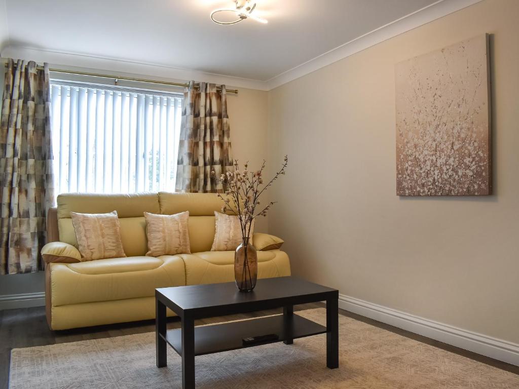 a living room with a yellow couch and a table at Buckthorn House in Middlesbrough