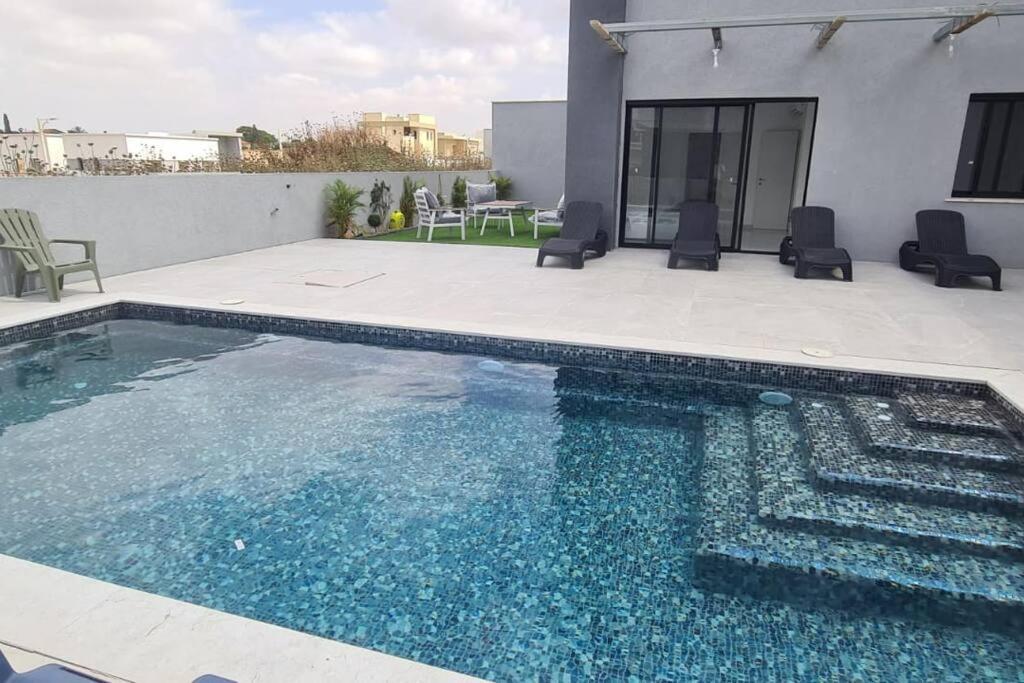 a swimming pool with blue water in front of a house at Luxurious Villa at the country side! in Tel Aviv