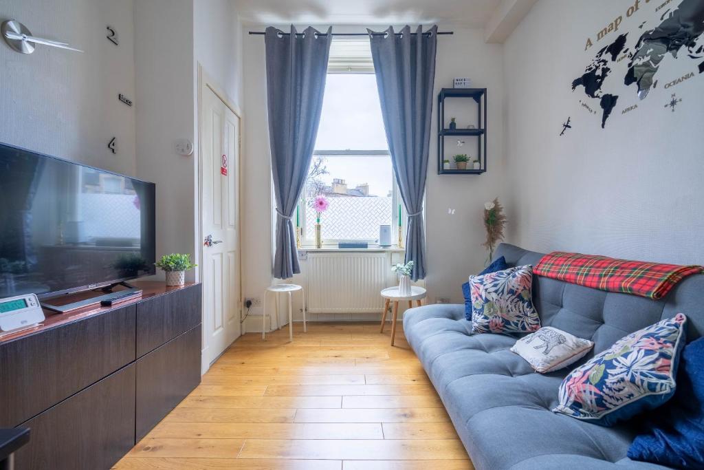een woonkamer met een blauwe bank en een televisie bij Cosy Leith Escape - Edinburgh City in Edinburgh